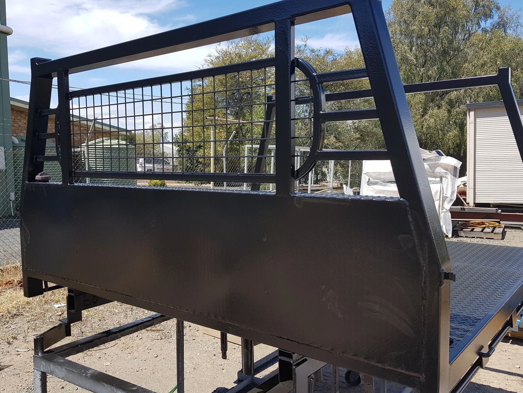 A black truck bed with a fence around it is sitting on the ground.