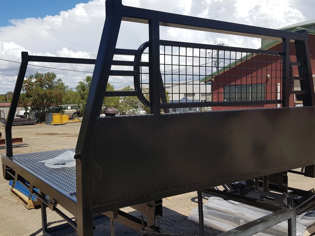 A black truck bed is sitting in a parking lot in front of a red building.
