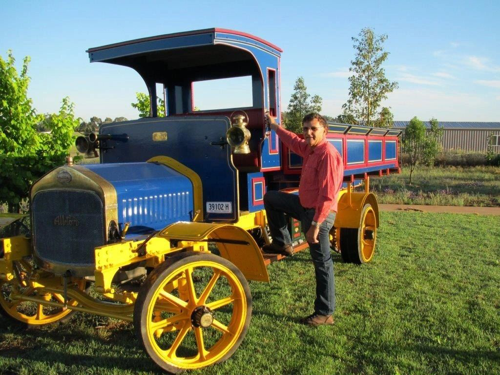 A man is standing next to a blue and yellow truck with a license plate that says ncr