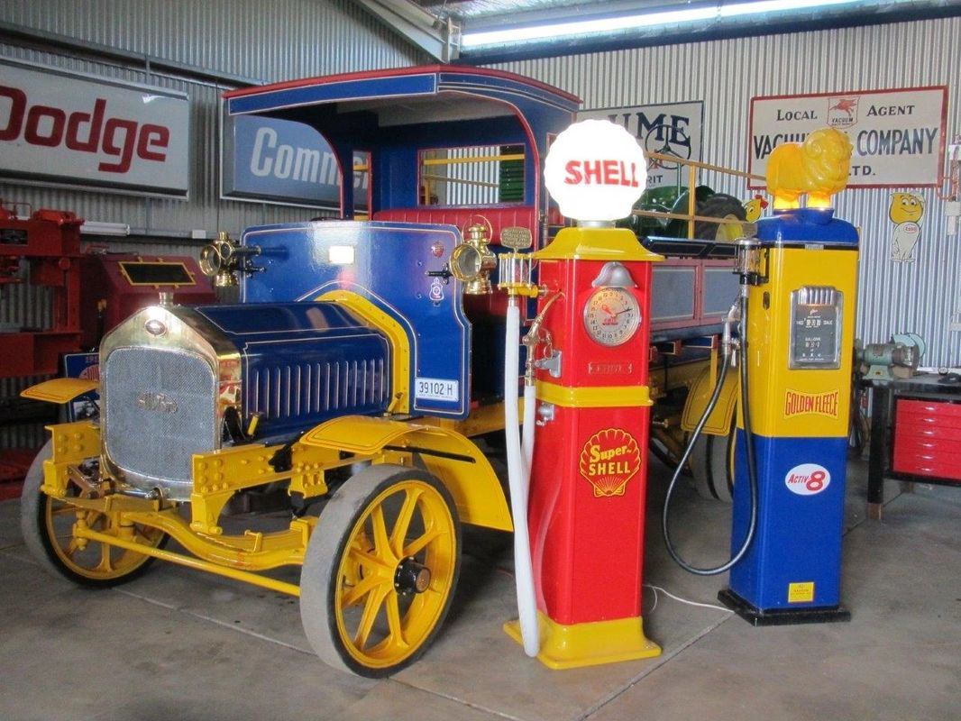An old car is parked next to a shell gas pump