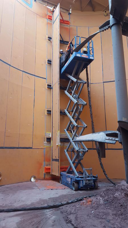 A man is standing on a scissor lift in a building.