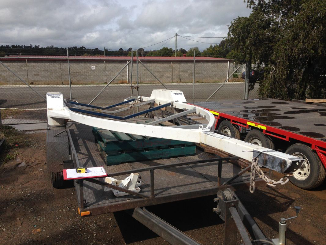 A boat trailer is sitting on top of a trailer in a parking lot.