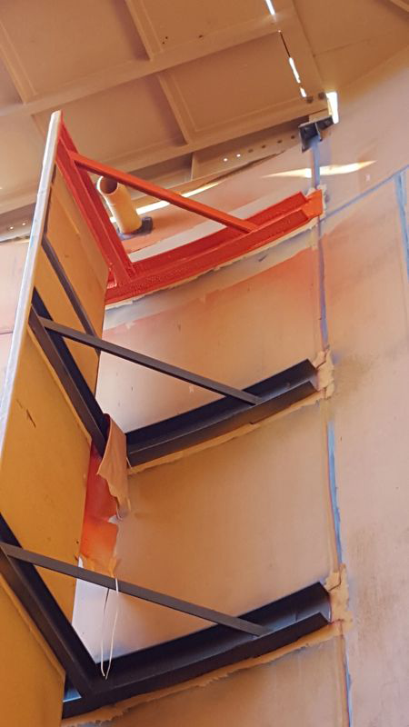 A close up of a wooden staircase with a metal railing.