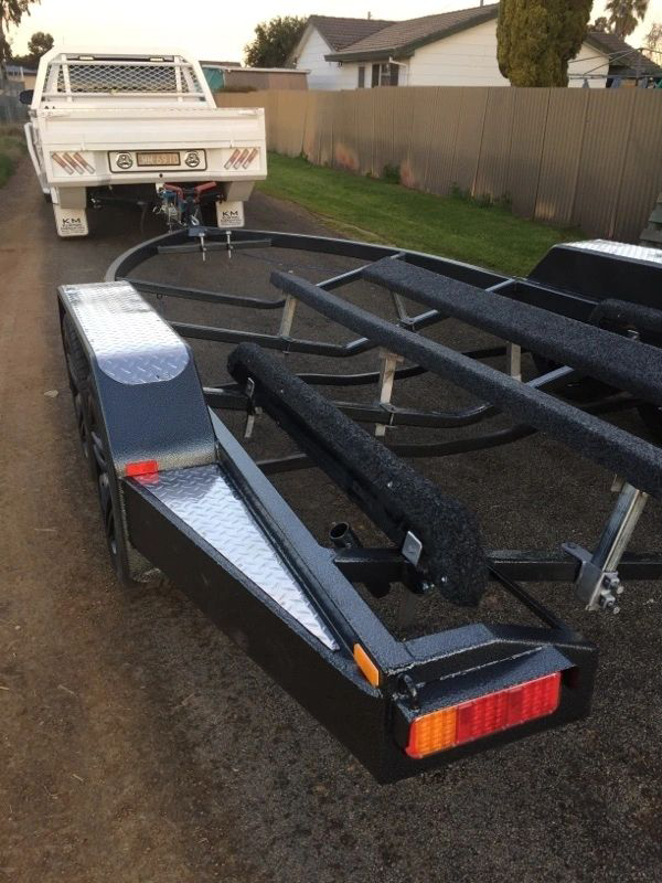 A white truck is parked next to a boat trailer