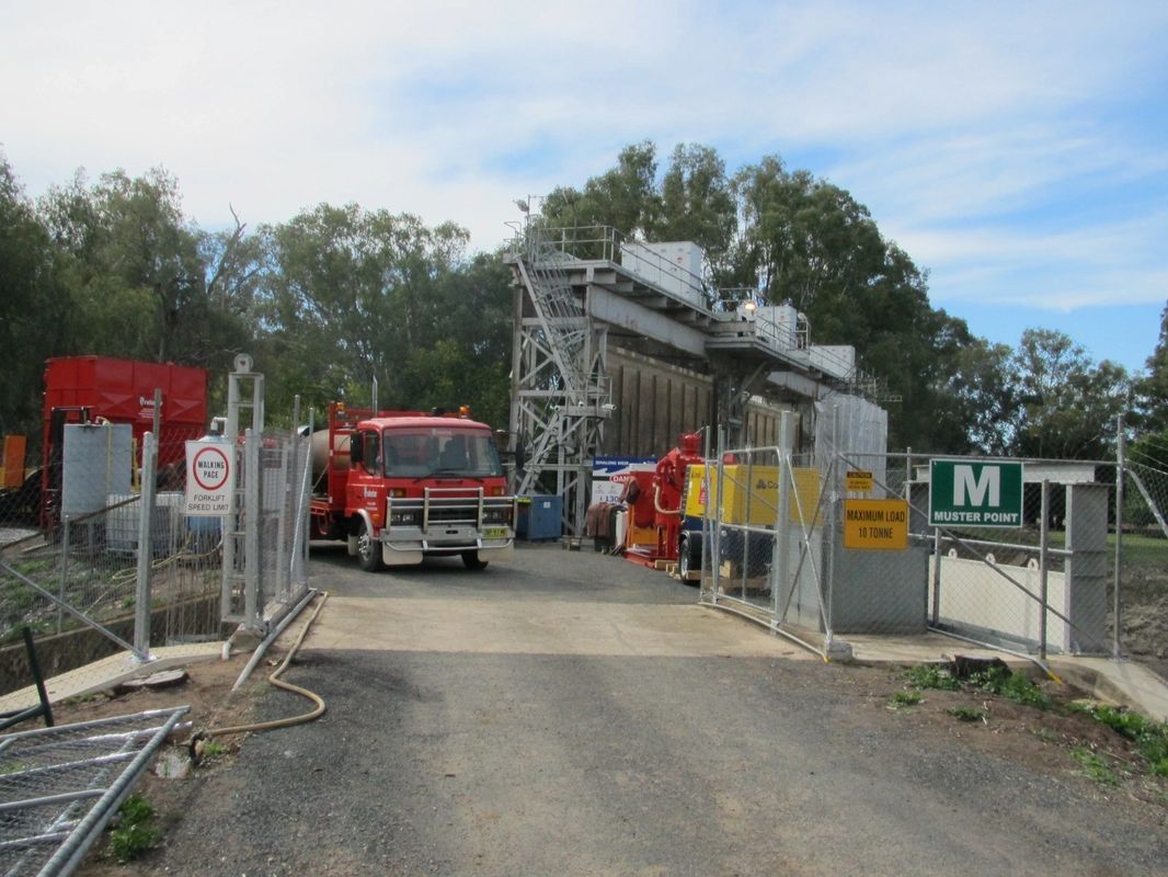 A red truck is parked in front of a fence with a sign that says m.
