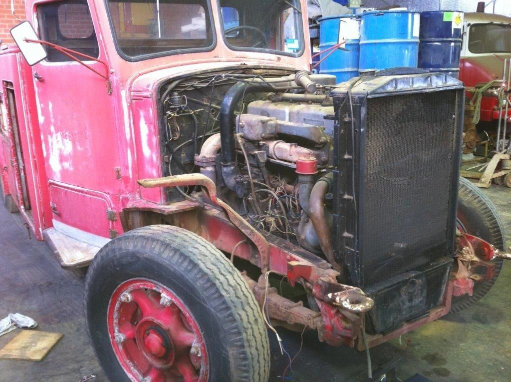 A red truck with the hood open is sitting in a garage