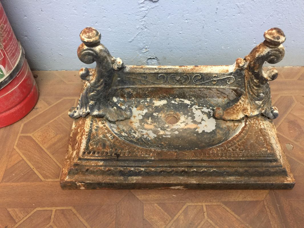 A rusty object is sitting on a wooden table next to a fire extinguisher.