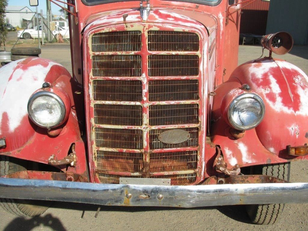 The front of an old red truck with a chrome bumper