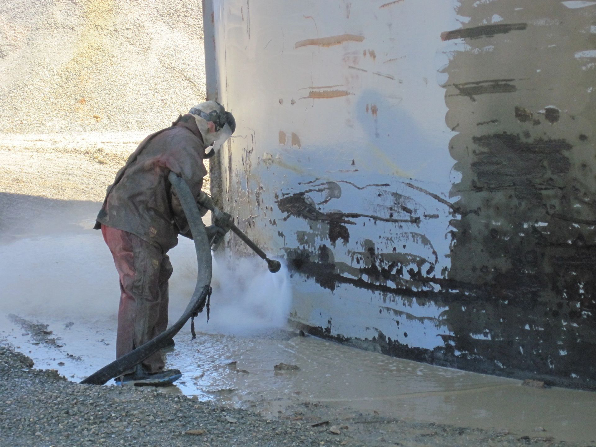 A man is spraying a wall with a hose