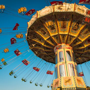 A merry go round at an amusement park with a blue sky in the background.