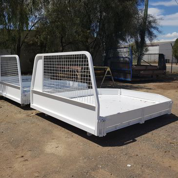 Two white trays are sitting on top of a dirt field.
