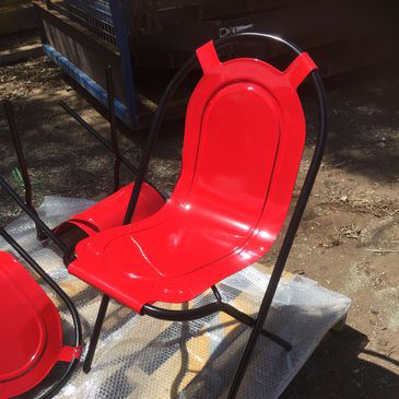 A red chair with a black frame is sitting on a pallet