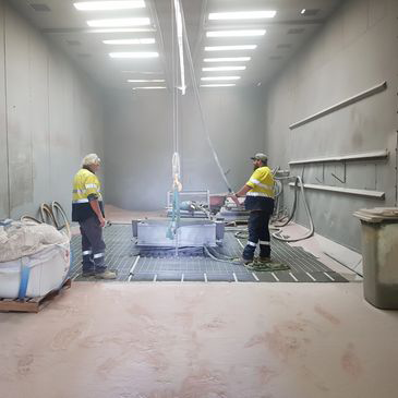 Two men are standing in a room with a machine.