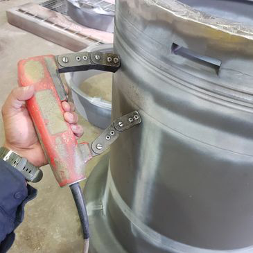A person is holding a magnet in front of a large metal object.