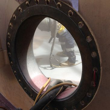 A man is working on a pipe through a round window