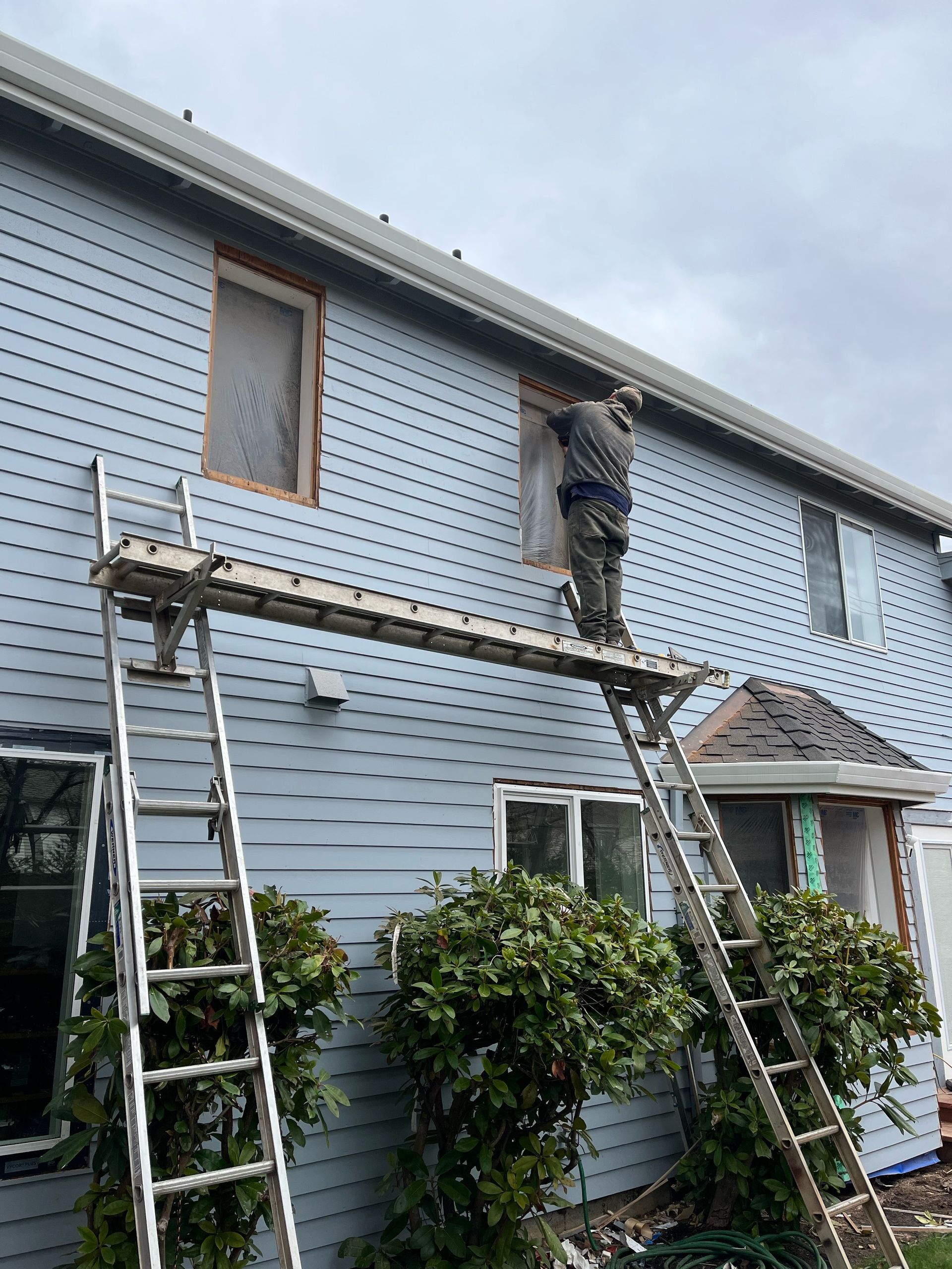 A man is standing on a scaffolding on the side of a house.