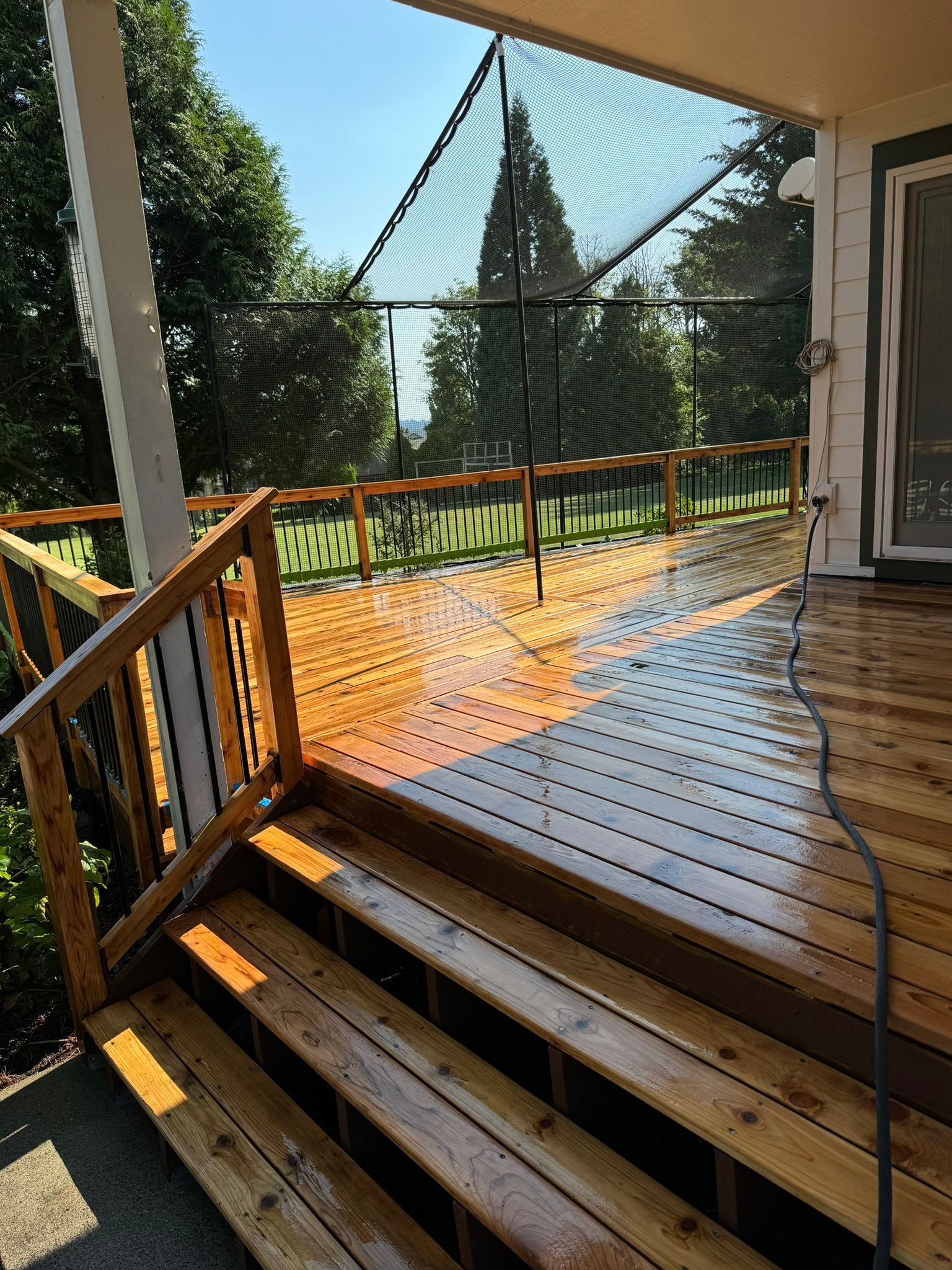 A wooden deck with stairs leading up to it and trees in the background.