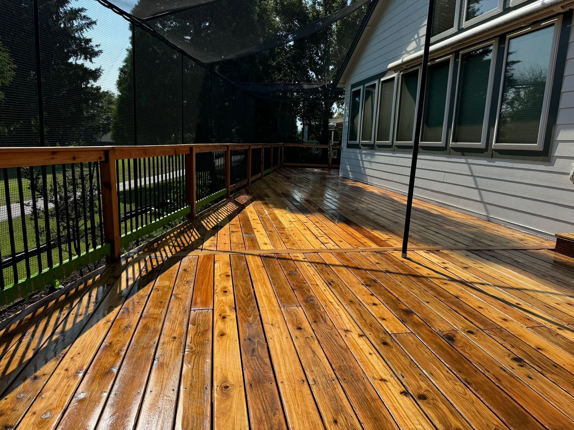 A wooden deck with a fence and a house in the background.