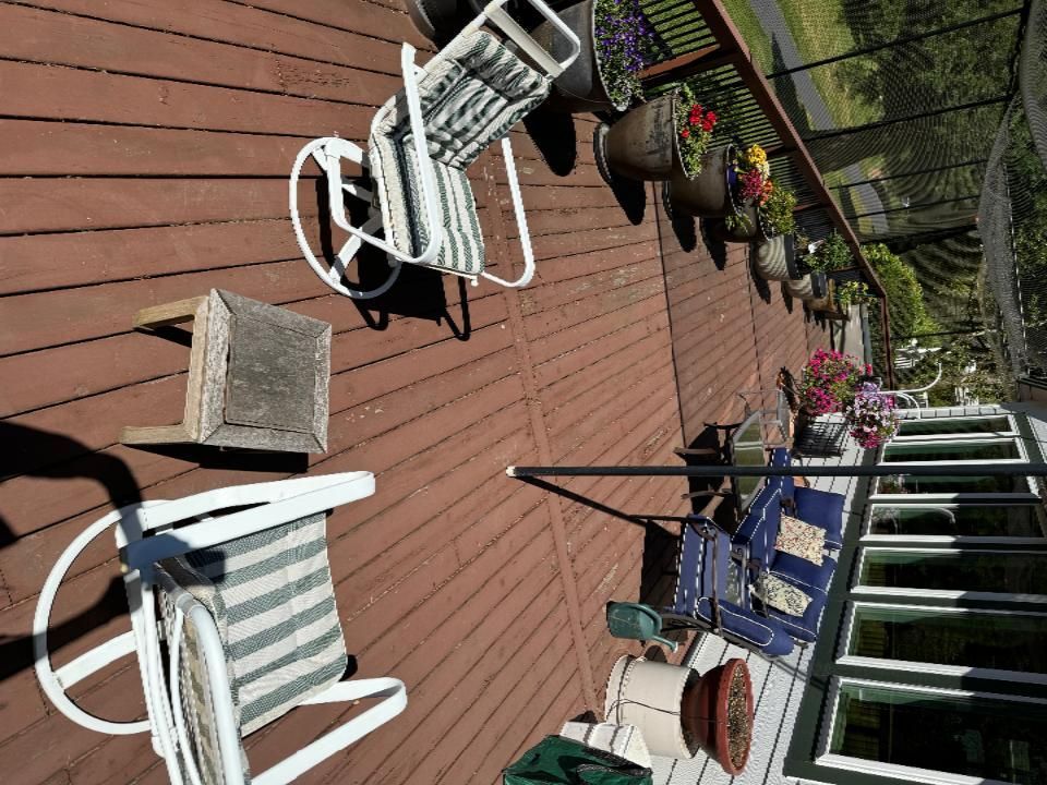A wooden deck with chairs and potted plants on it