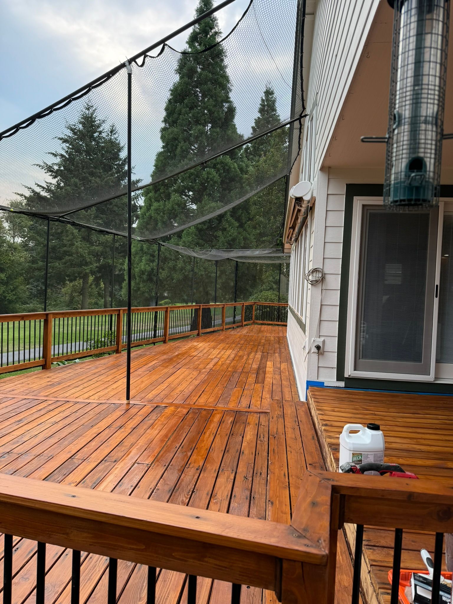 A wooden deck with a fence around it and trees in the background.