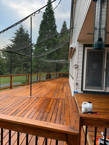 A wooden deck with a fence around it and trees in the background.