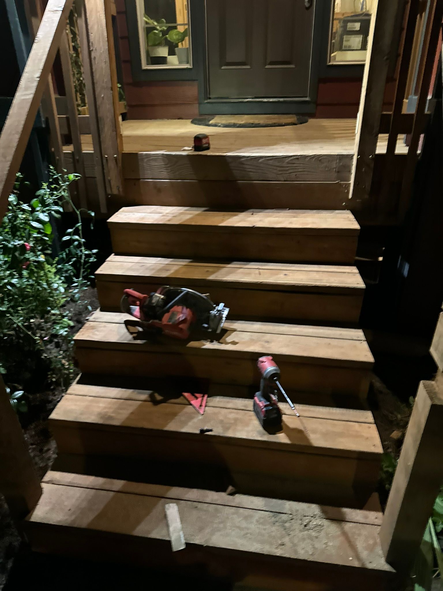 A set of wooden stairs leading up to a house at night.