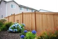 A wooden fence with flowers in front of a house.