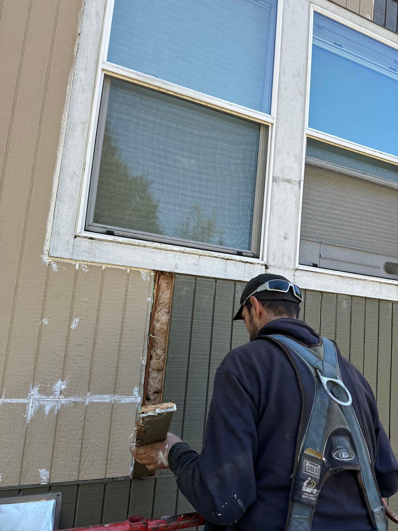 A man is working on a window on the side of a building.