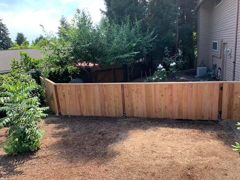 A wooden fence is in the backyard of a house.
