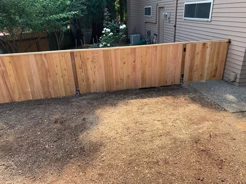 A wooden fence is in the backyard of a house.