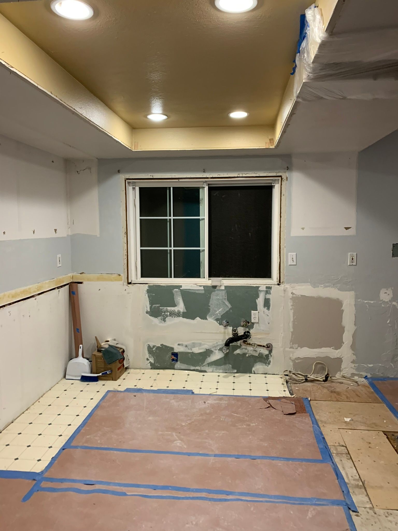A kitchen under construction with a window and a tile floor
