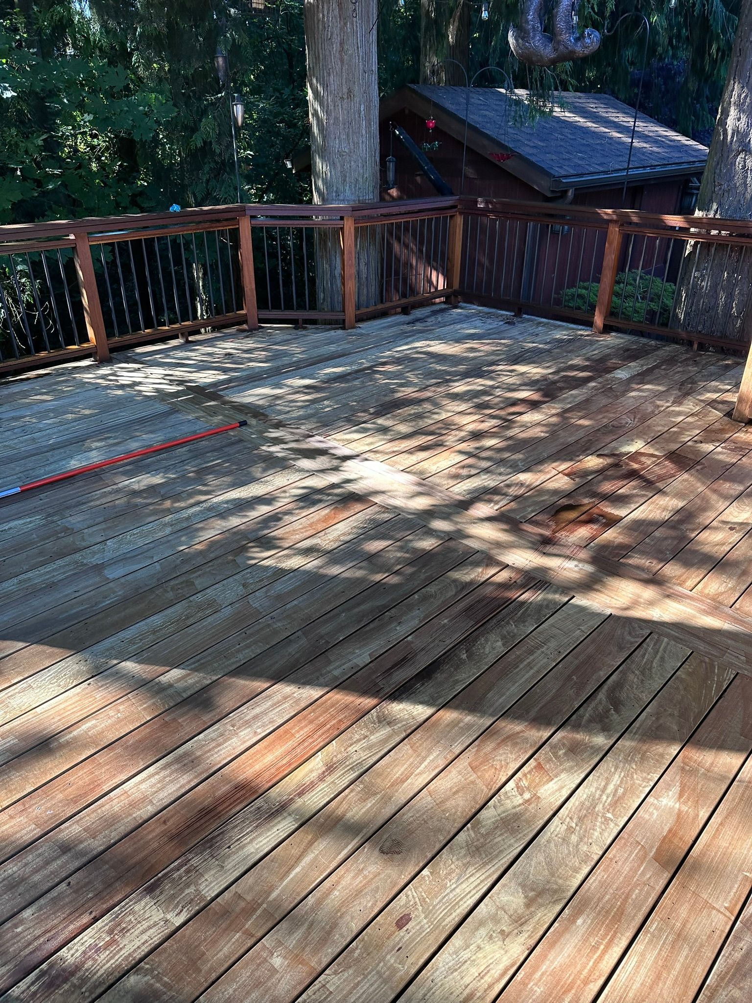 A wooden deck with a fence and trees in the background.