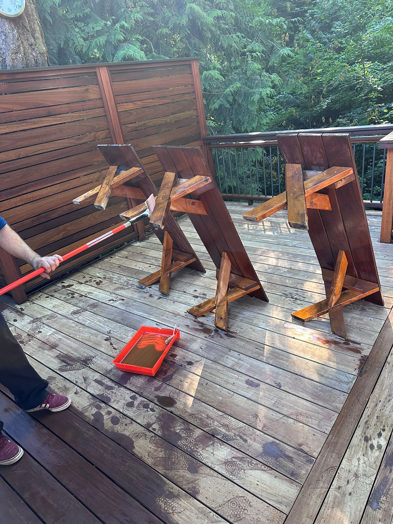 A person is cleaning a wooden deck with a broom.