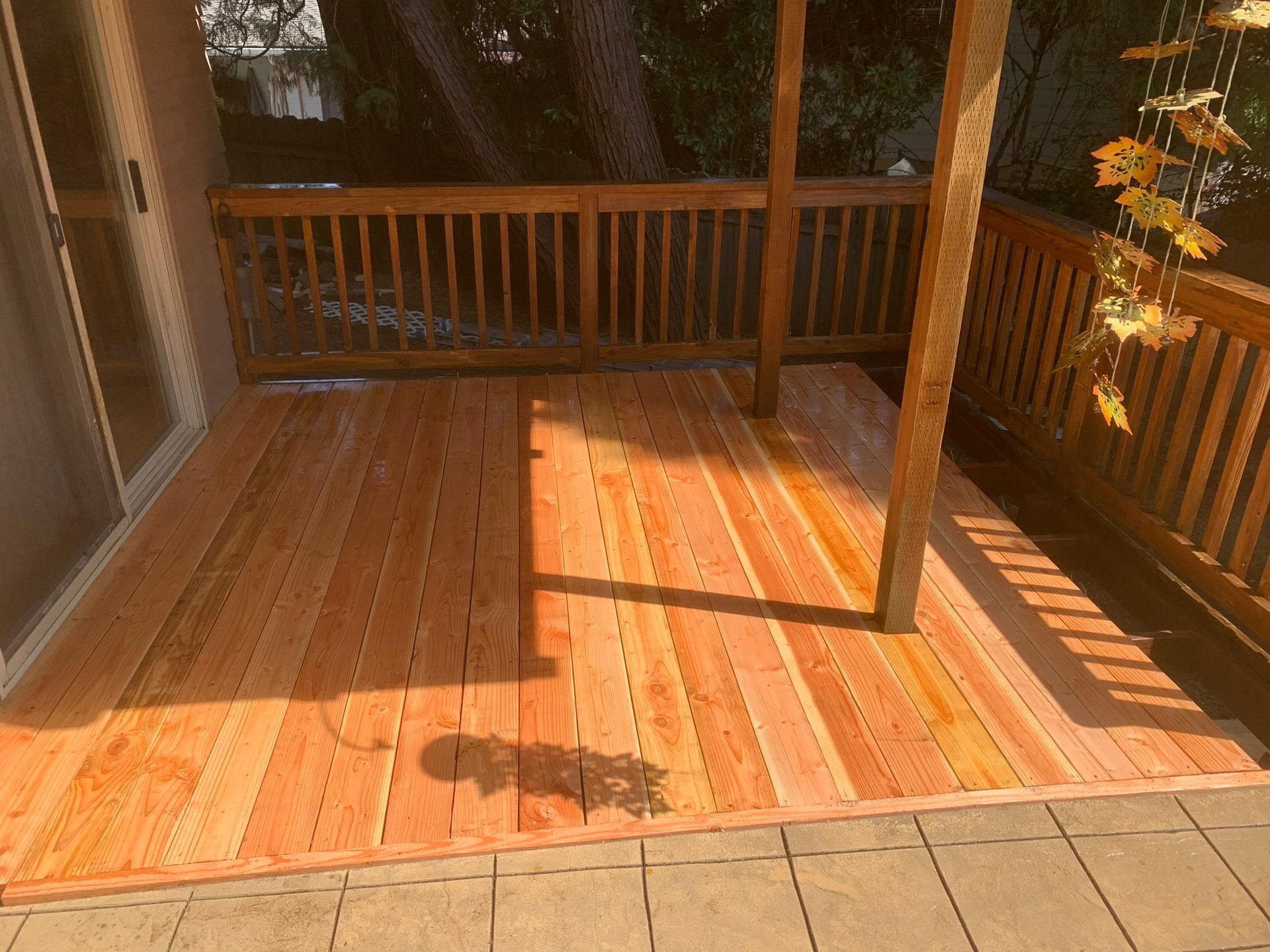 A wooden deck with a railing and a sliding glass door.