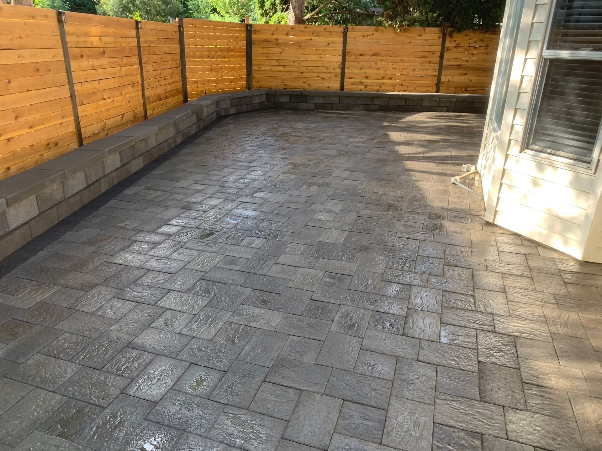 A brick patio with a wooden fence in the background.