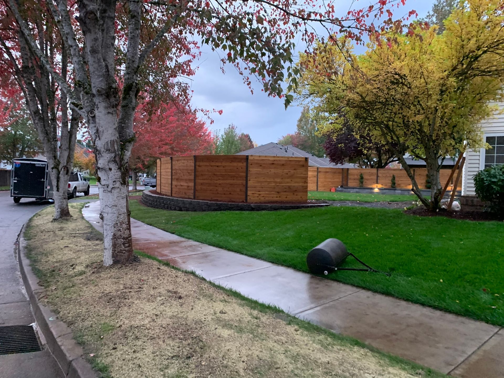 A lawn mower is sitting on the sidewalk next to a lush green lawn.