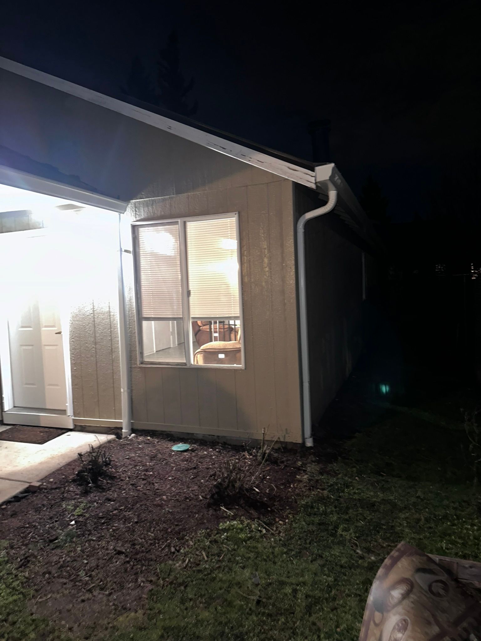 A house with a shed in the backyard at night.