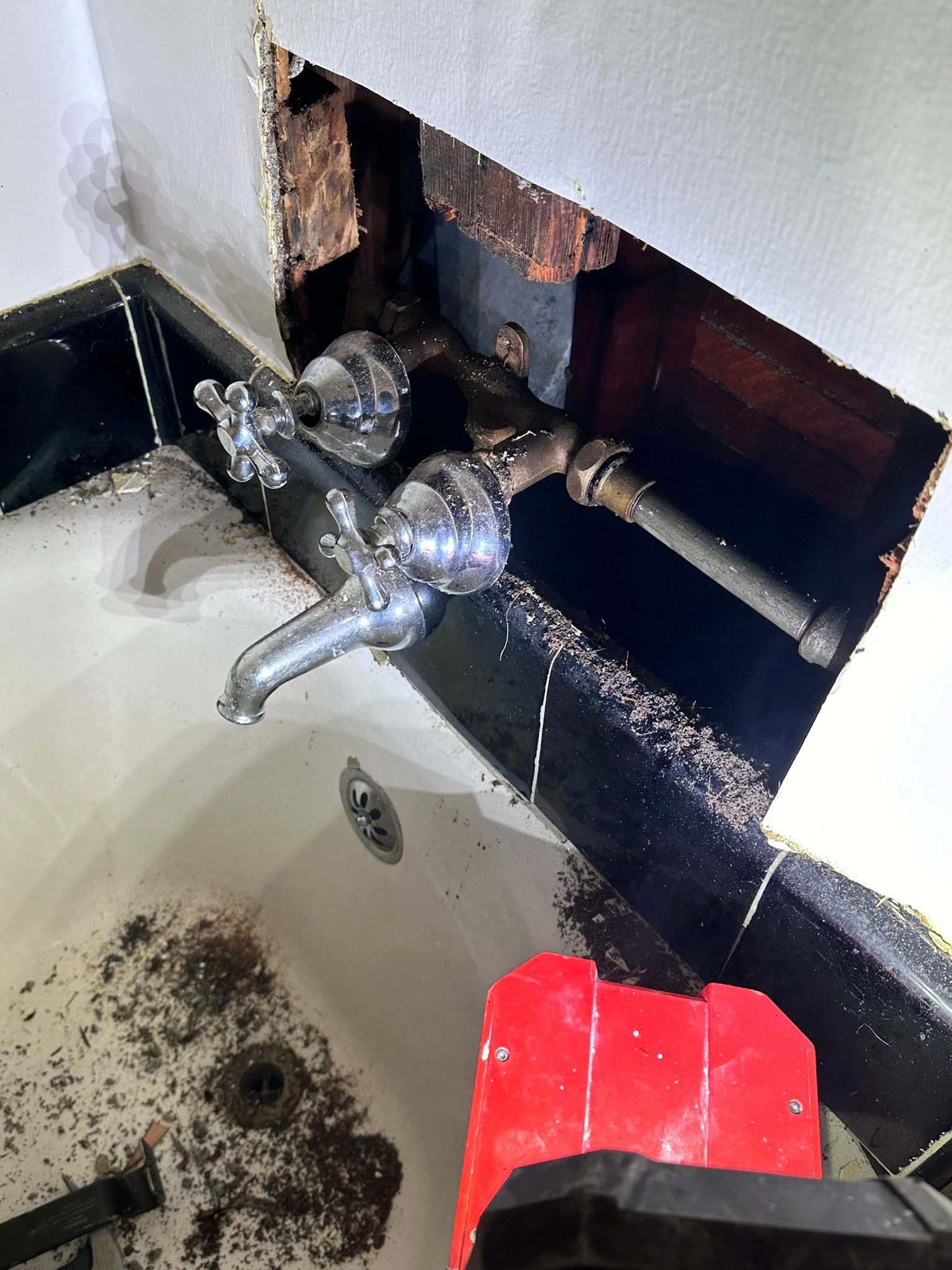 A bathroom sink with a faucet missing and a hole in the wall.