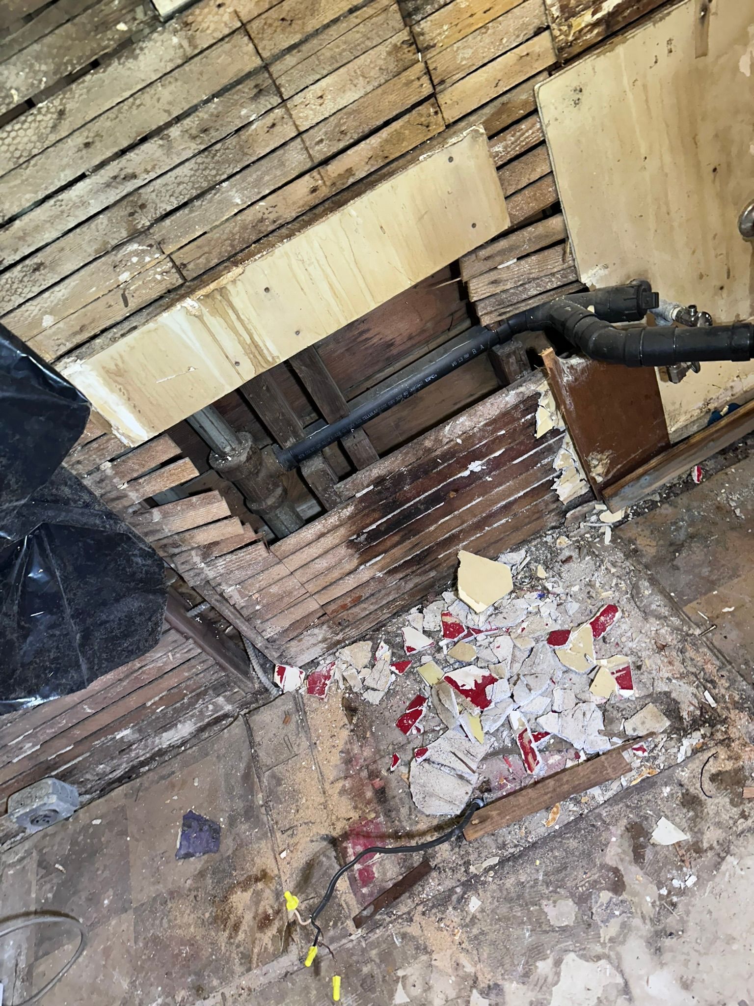 A wooden floor with a hole in it and a pipe coming out of it.