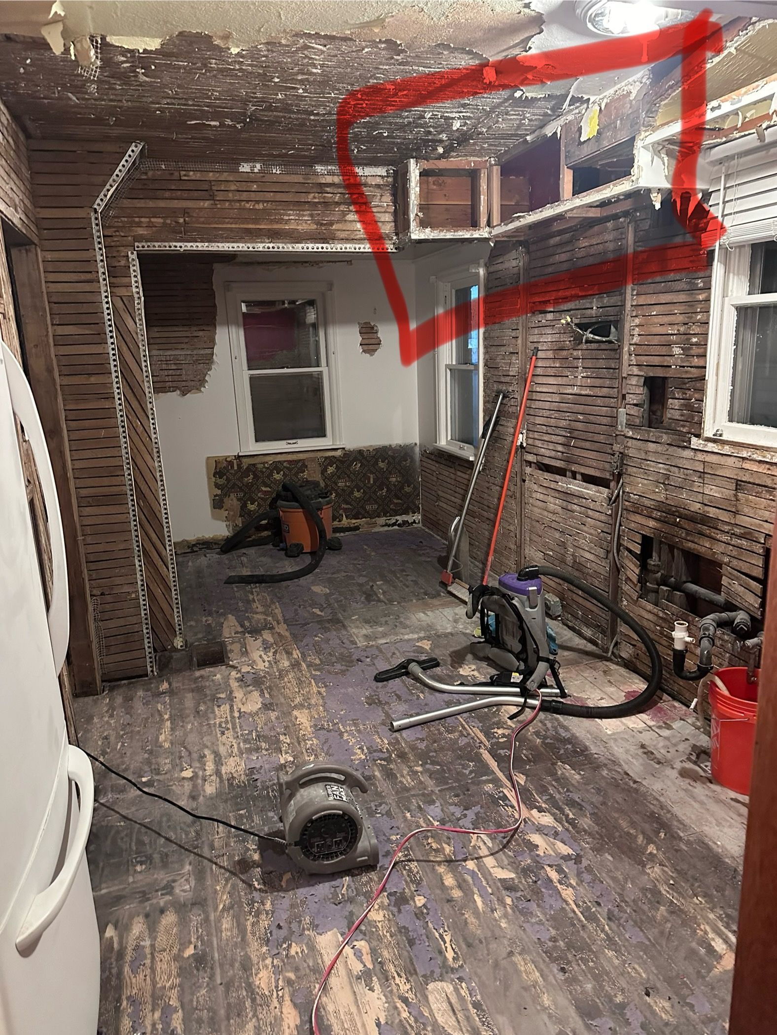 A room with a vacuum cleaner on the floor and a red arrow pointing to the ceiling.