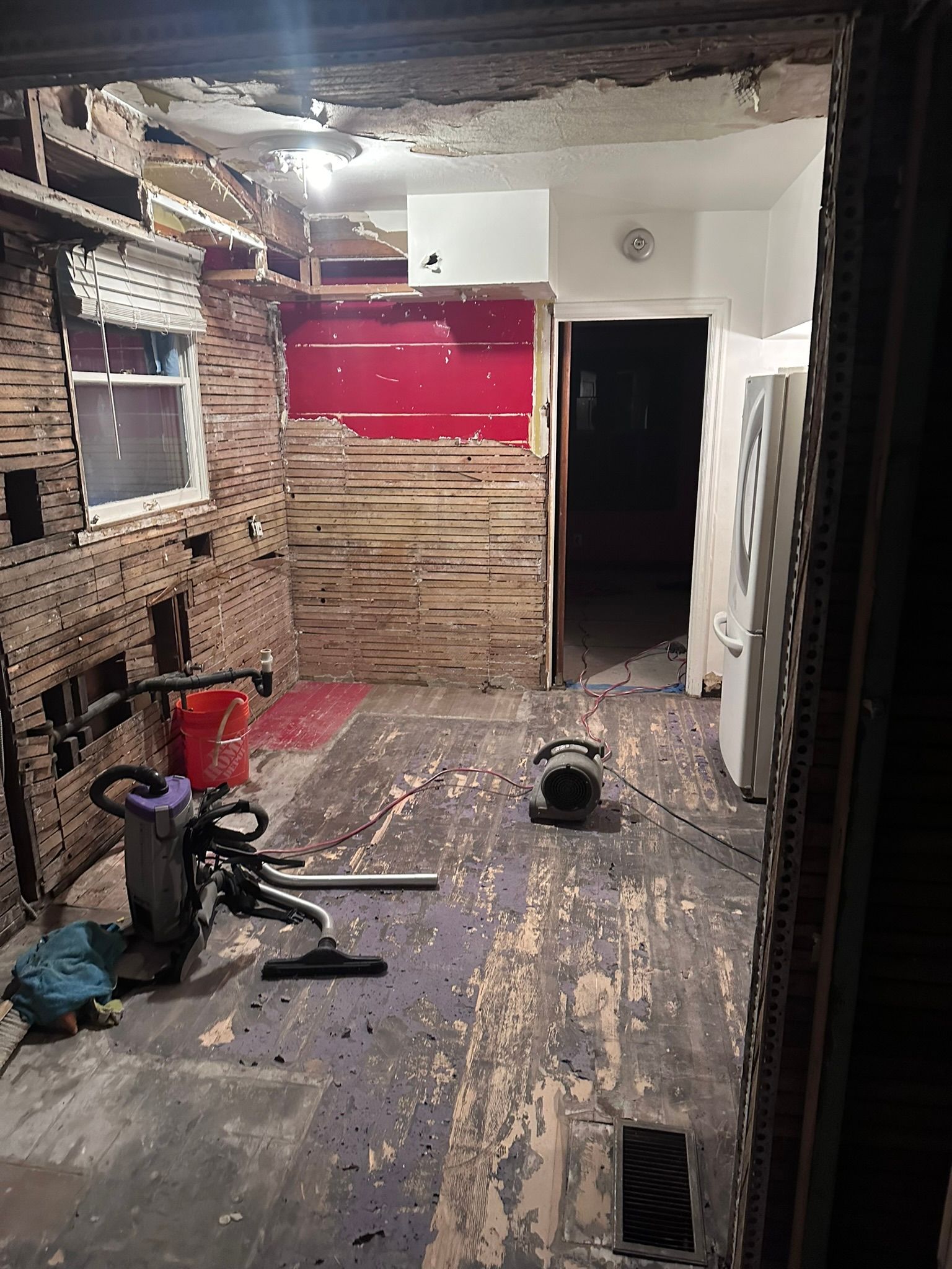 A room with a vacuum cleaner and a bucket on the floor.