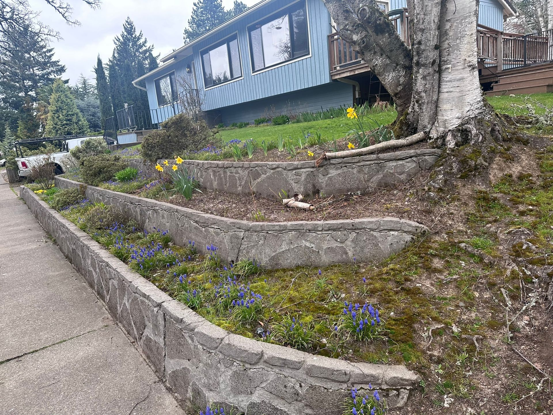 A house is sitting on top of a hill next to a stone wall.