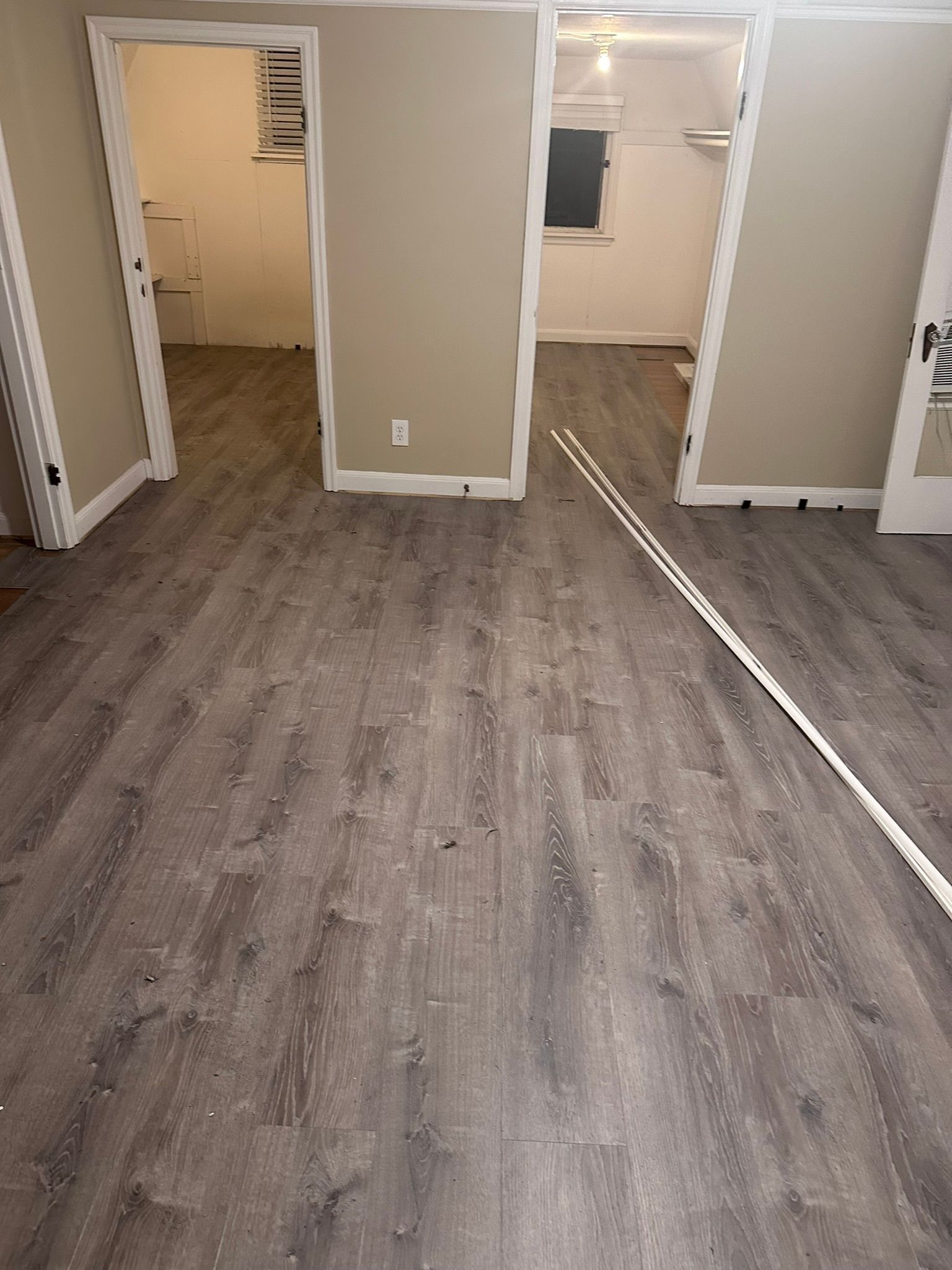 A room with a wooden floor and a rope between two doors.