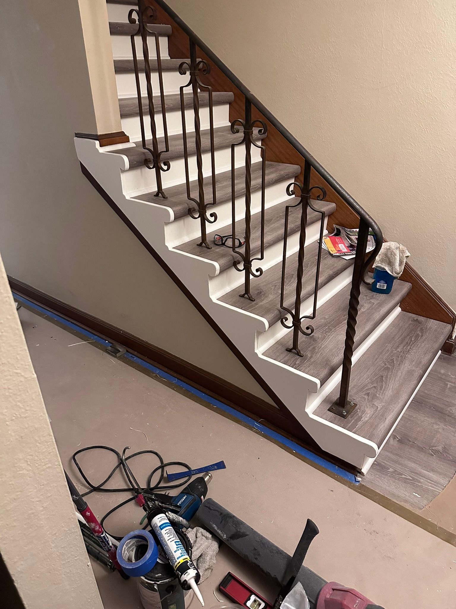 A staircase with a wrought iron railing is being painted.