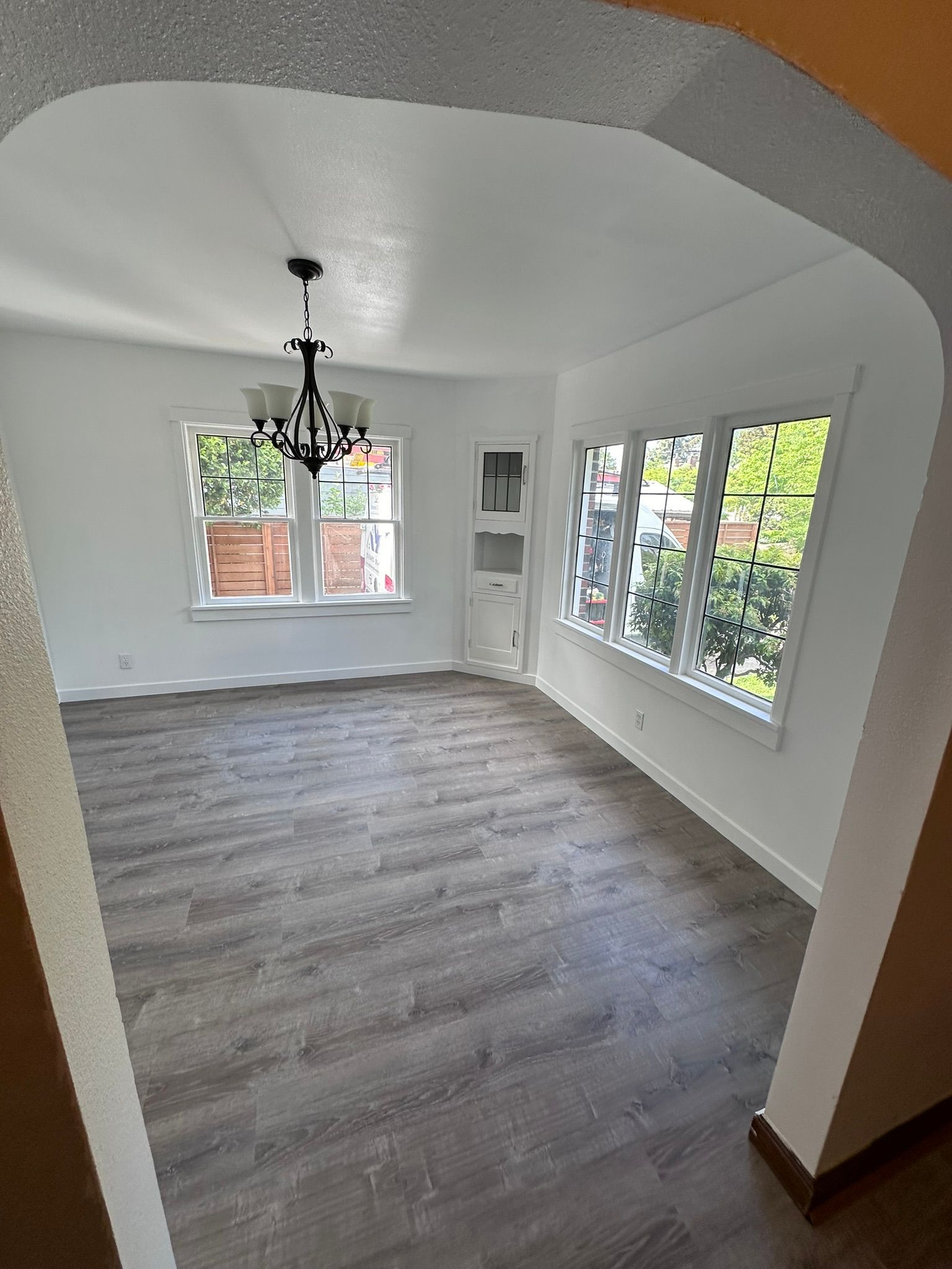 An empty living room with hardwood floors and a chandelier.
