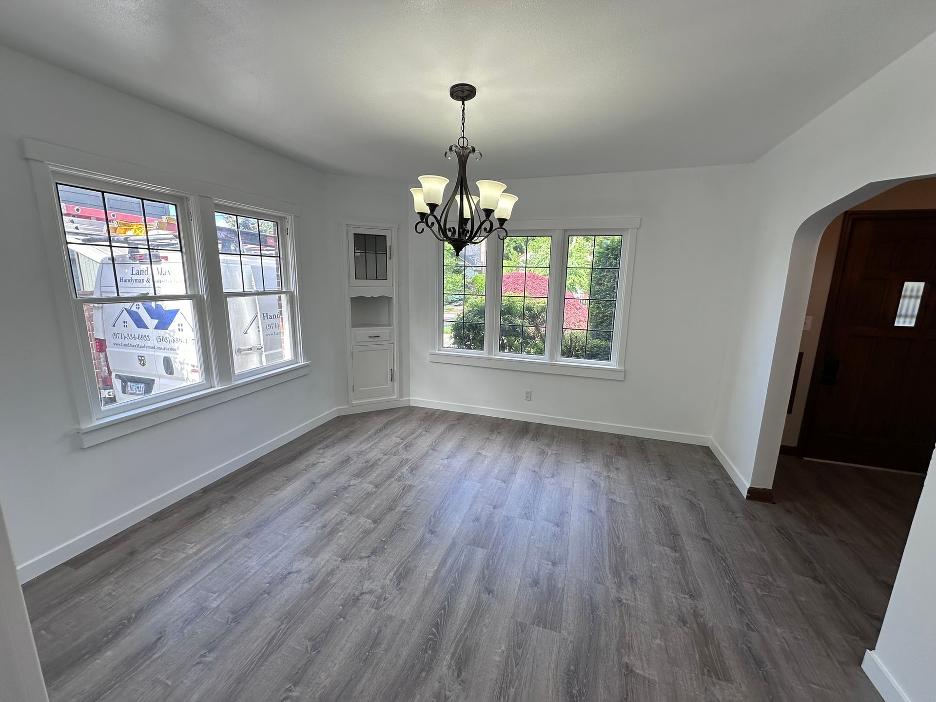 An empty living room with a chandelier hanging from the ceiling.