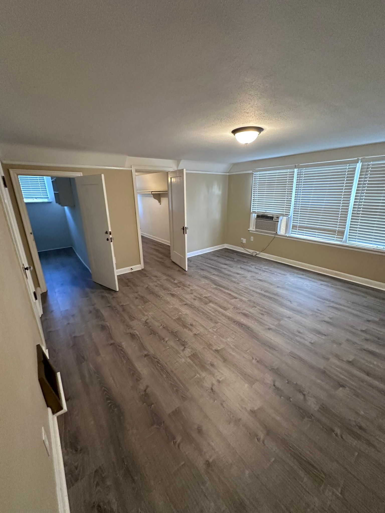 An empty living room with hardwood floors and a window.