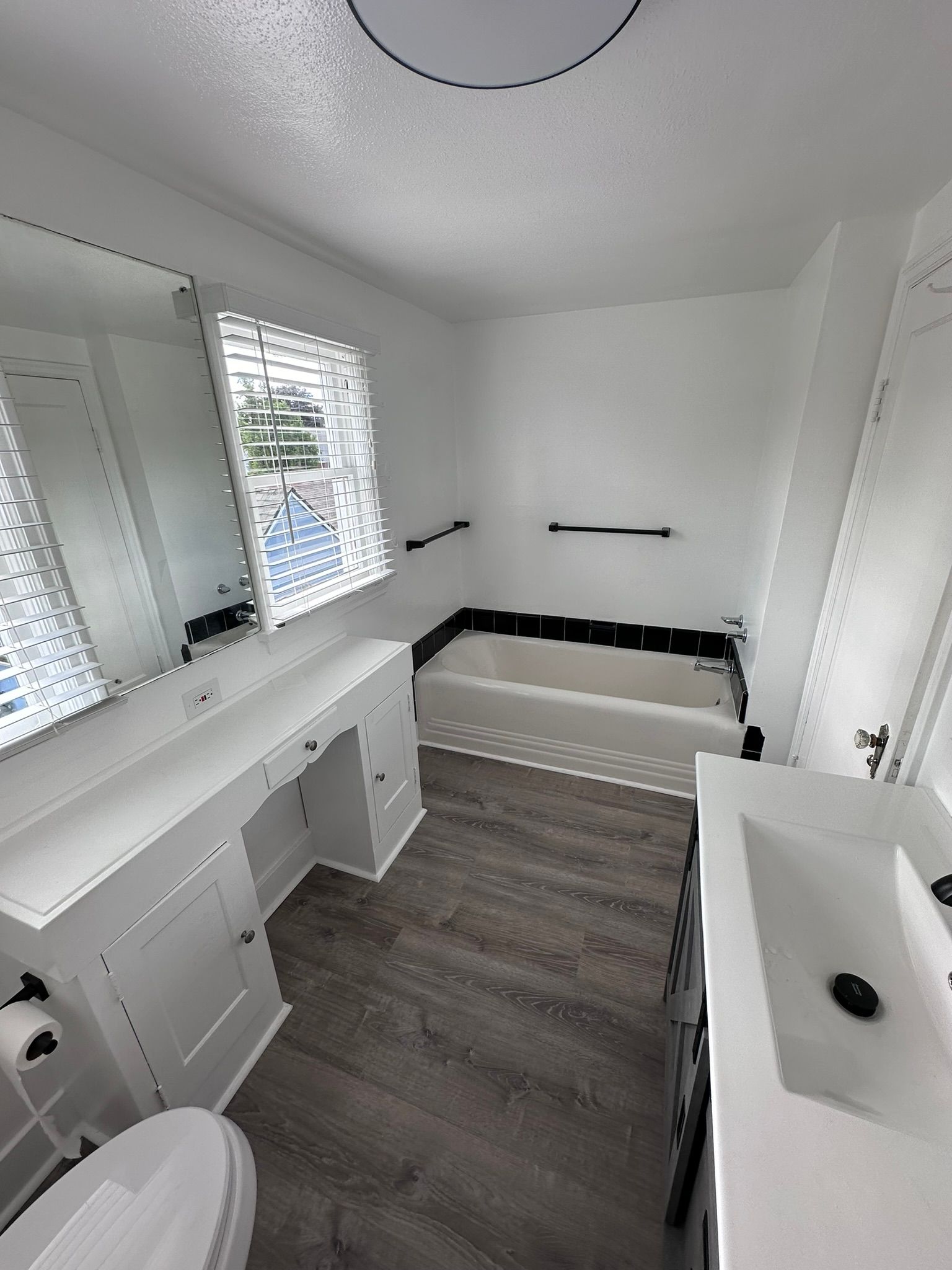 A bathroom with a tub , sink , toilet and mirror.