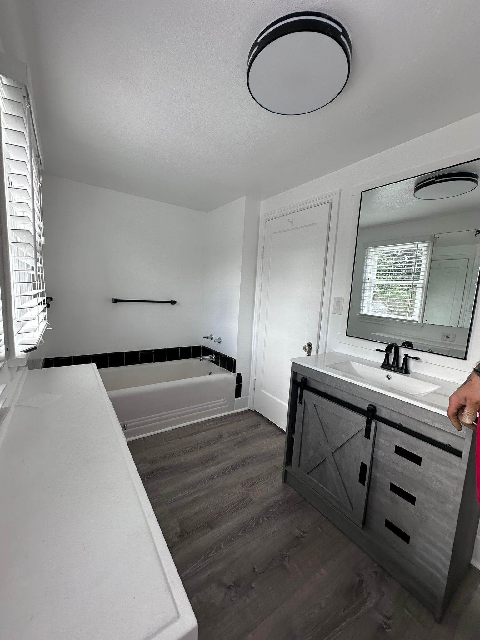 A bathroom with a sink , tub and mirror.