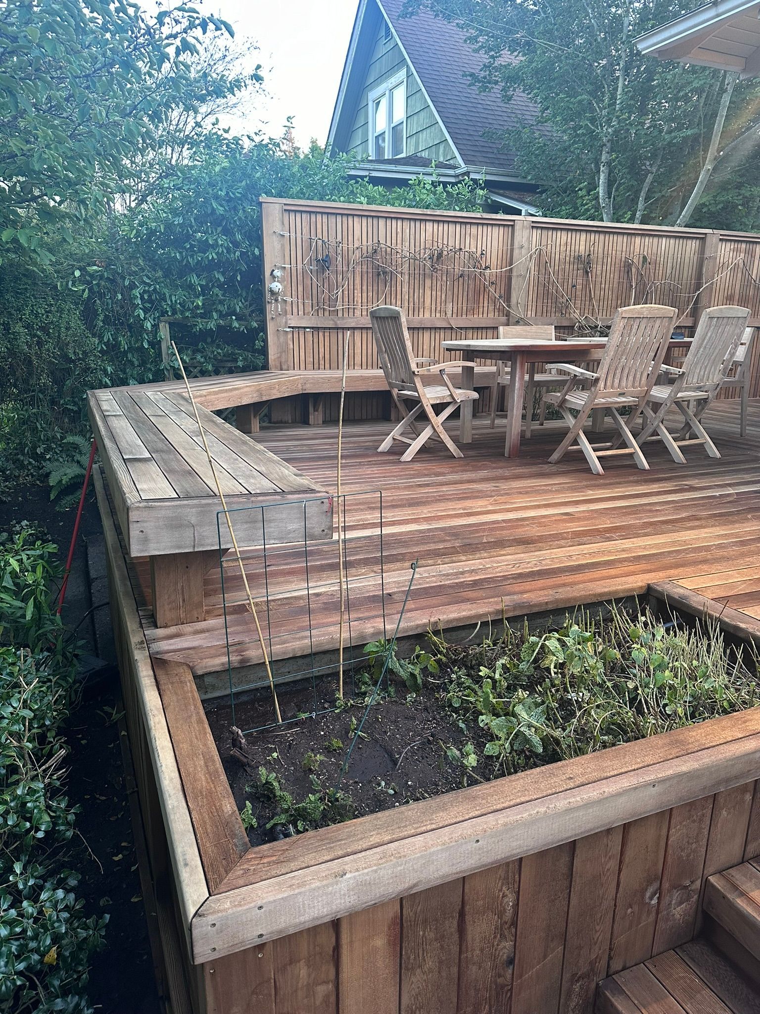 A wooden deck with a table and chairs and a bench.